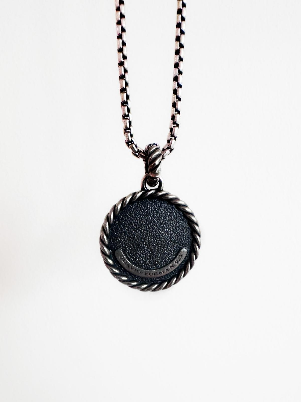 Back side of DY silver pendant initial M on silver chain and white background , shows DY signature