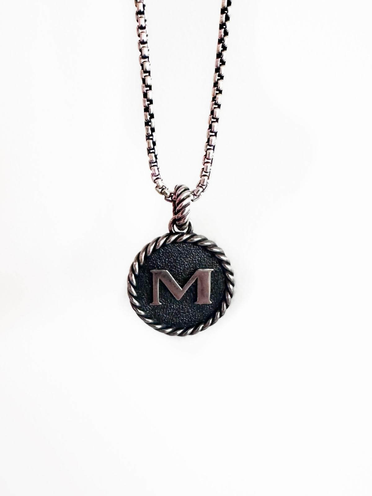 DY silver pendant initial M on silver chain and white background 