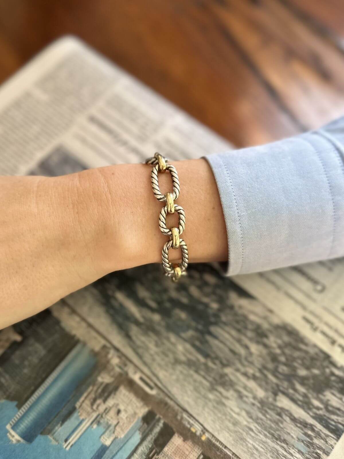 Gold chain bracelet on a wrist with a blurred background