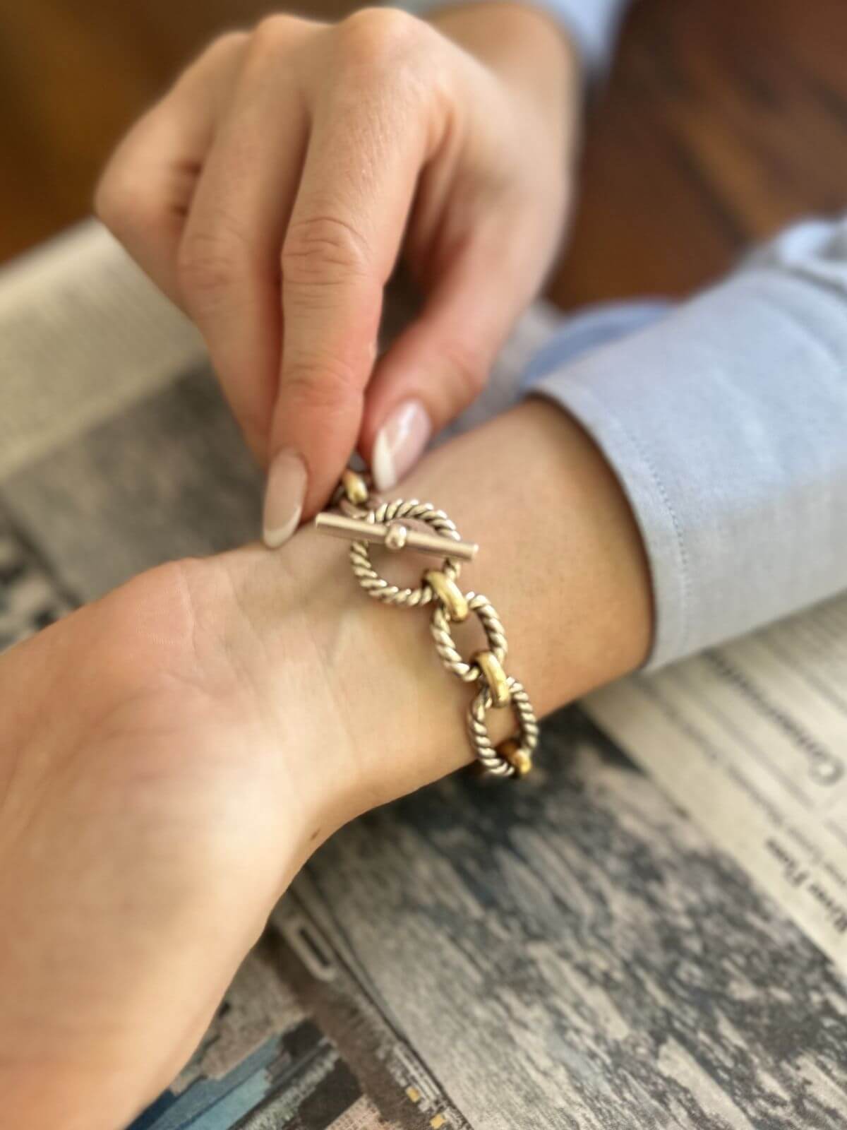 Gold bracelet being worn on a wrist with a blurred background