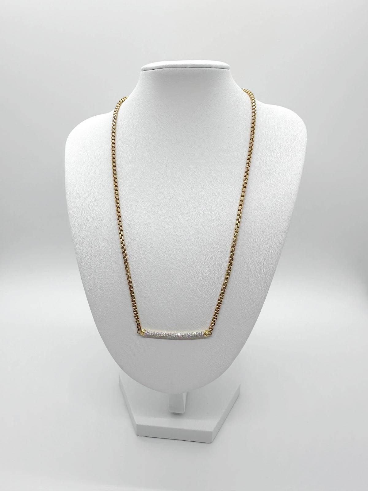 DY diamond bar on Gold chain necklace on a white mannequin bust against a white background
