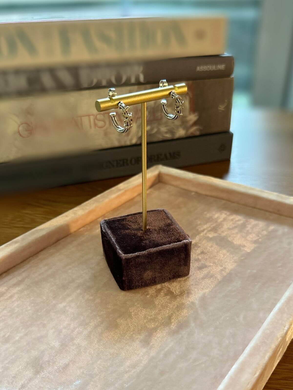 David Yurman Helena silver and gold small hoops on fixture with books in background