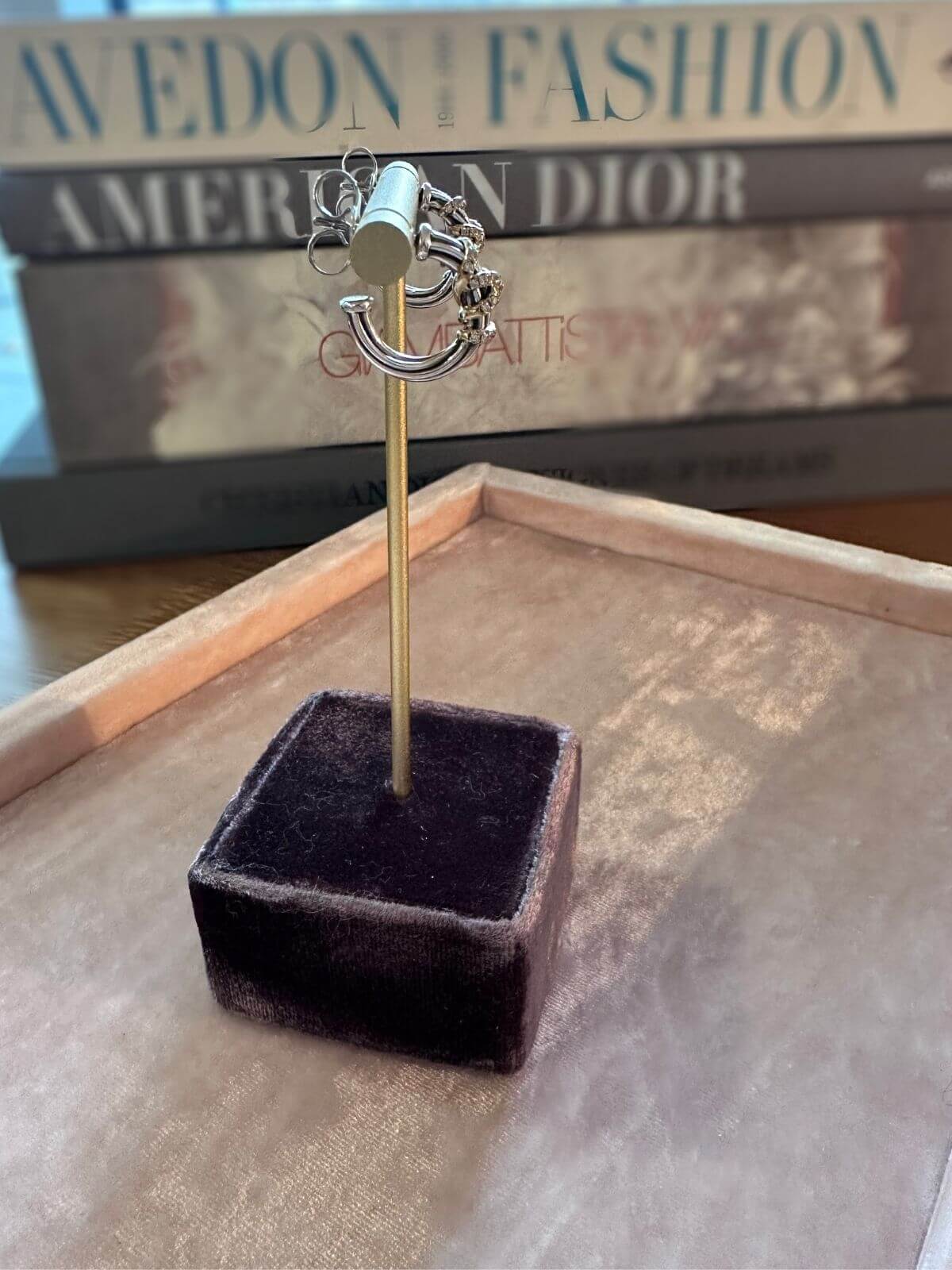 David Yurman Helena silver and gold small hoops on fixture with books in background