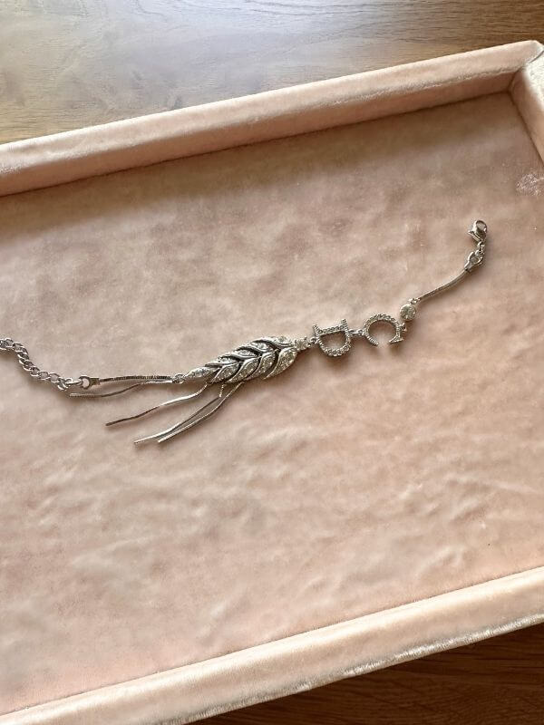 Louise Row Studio featuring Dior silver feather inspired bracelet made of silver and crystals on pink display pad. 