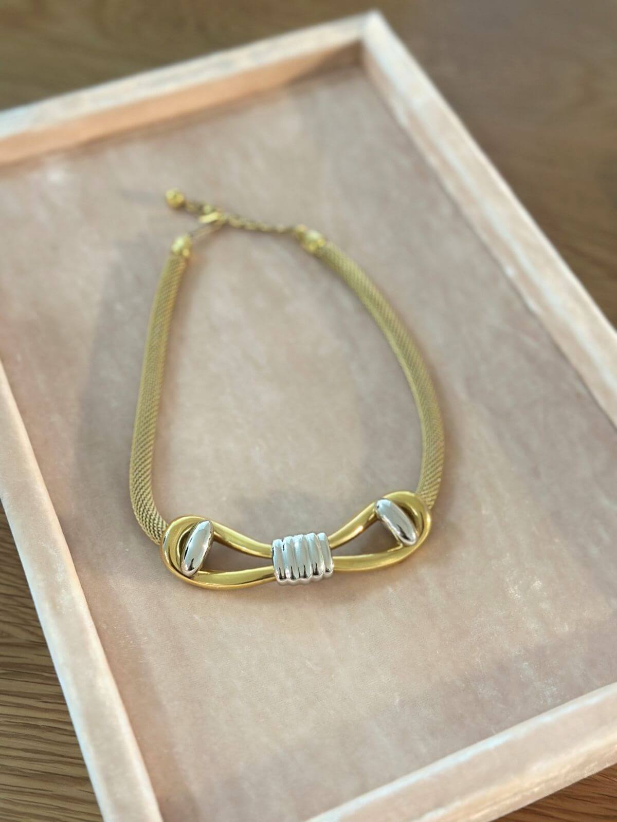 Louise Row Studio Vintage Givenchy necklace of  gold 2 tone bow design on pink tray.