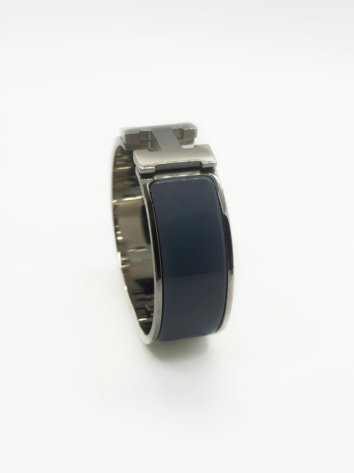 Hermes Clic H Bracelet in stainless steel and enamel on white background. Grey enamel with H in center. 