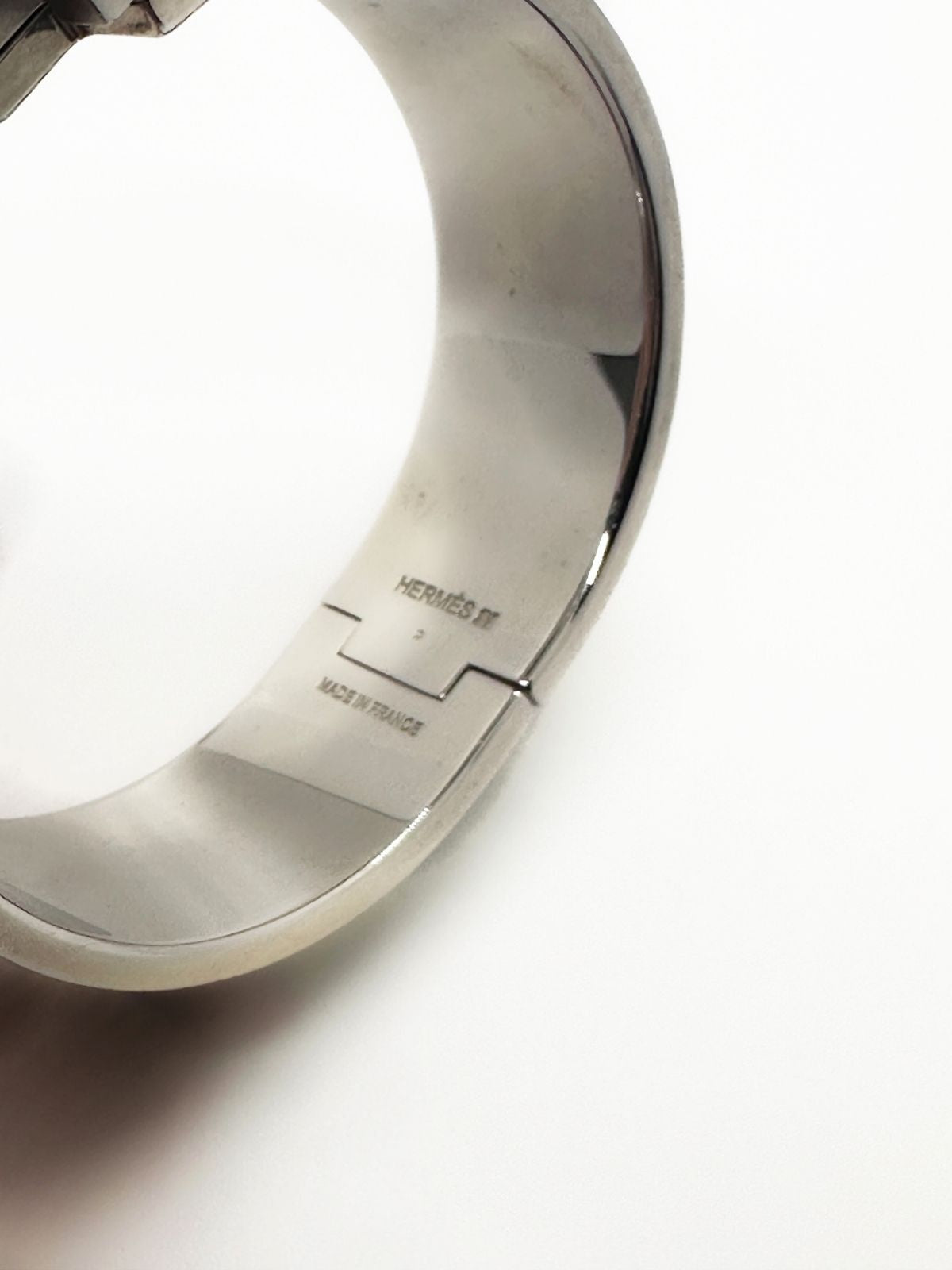 Hermes Clic H Bracelet in stainless steel and enamel on white background. Grey enamel with H in center. 