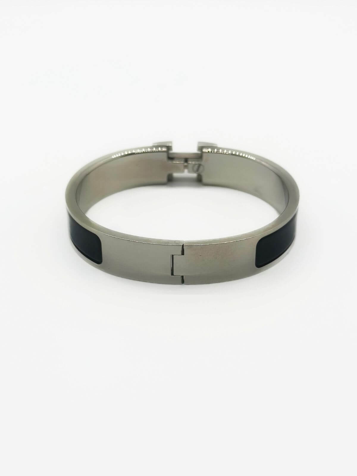 Hermes Clic H bracelet in stainless steel and black enamel on white background. 