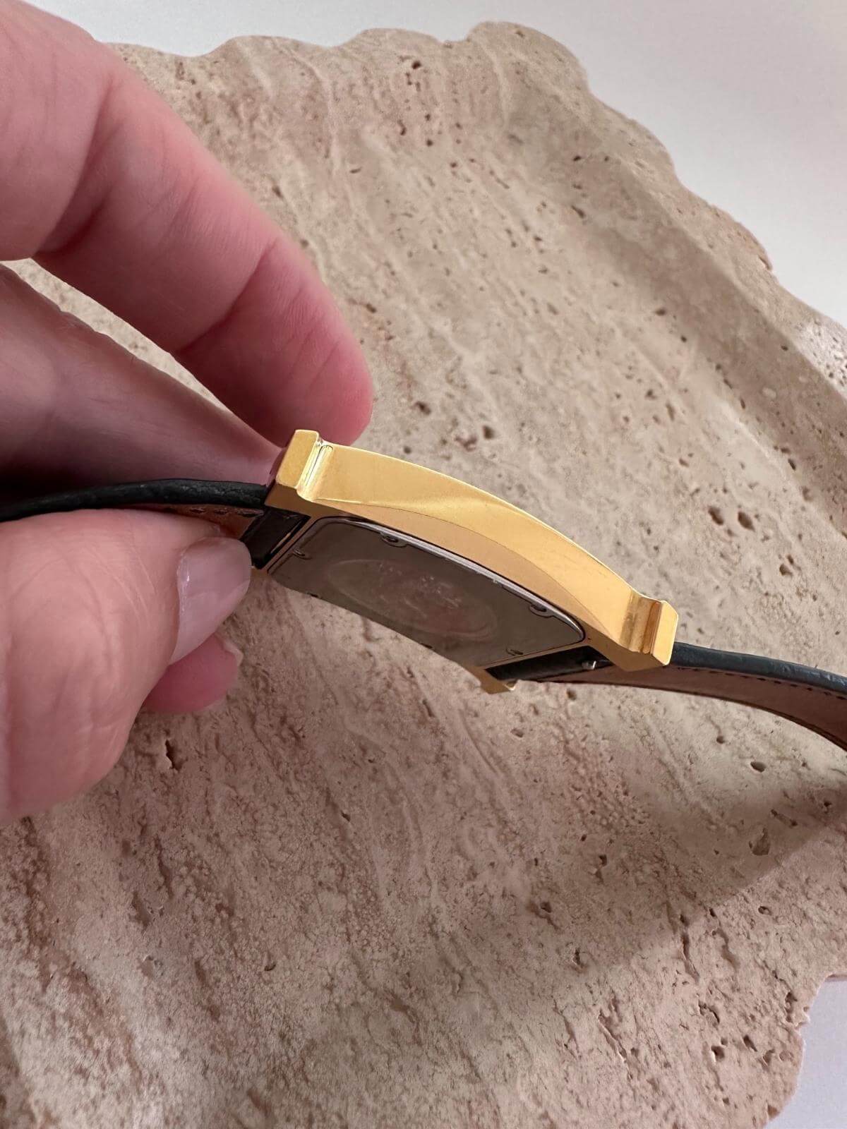 Side of Hermes Gold watch band being adjusted on a marble tray