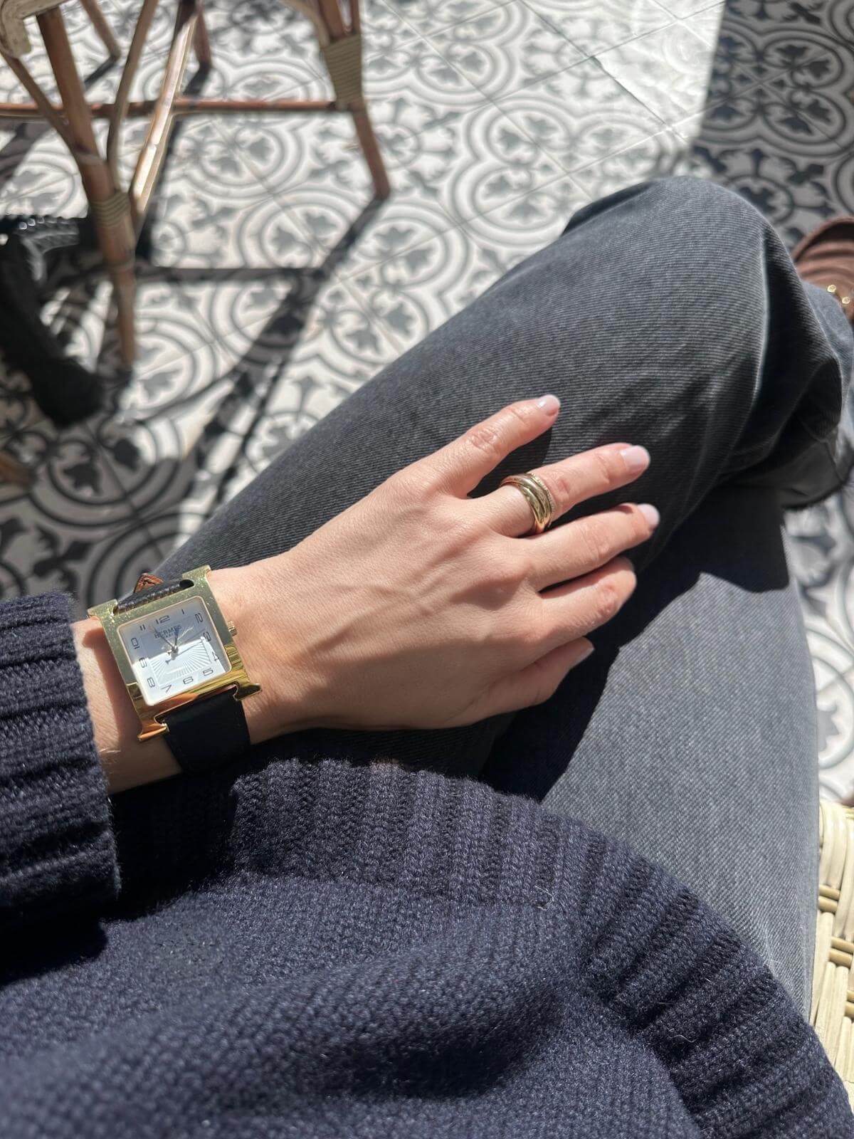 Model wearing Hermes H Heure gold watch on jeans with pattern background