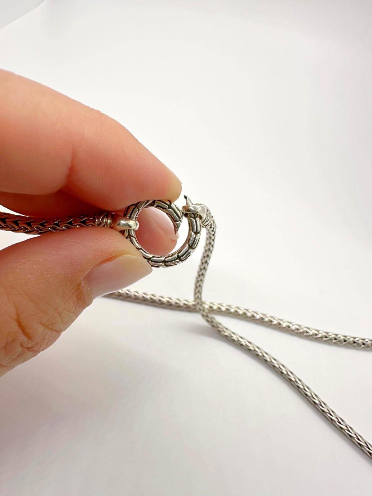 hand showing John Hardy detail of clasp silver necklace and white background