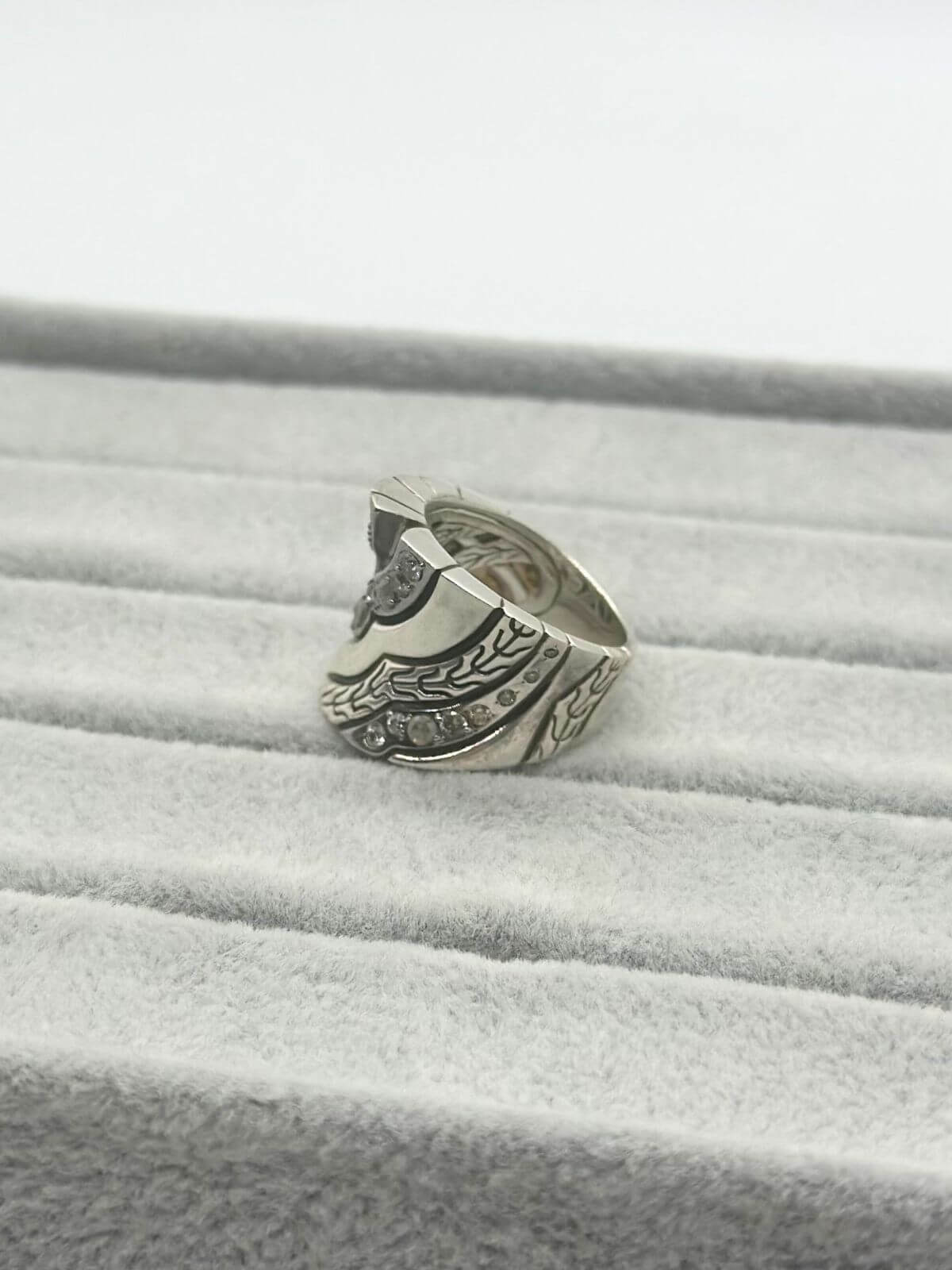 John Hardy silver and diamond ring on grey fixture. Side View.