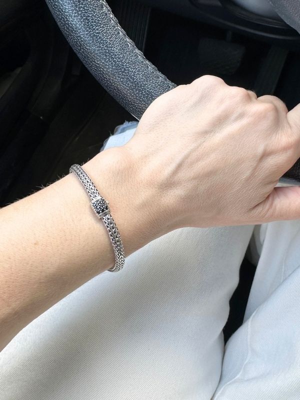 Louise Row Studio featuring John Hardy silver chain bracelet with sapphire on arm holding steering wheel.