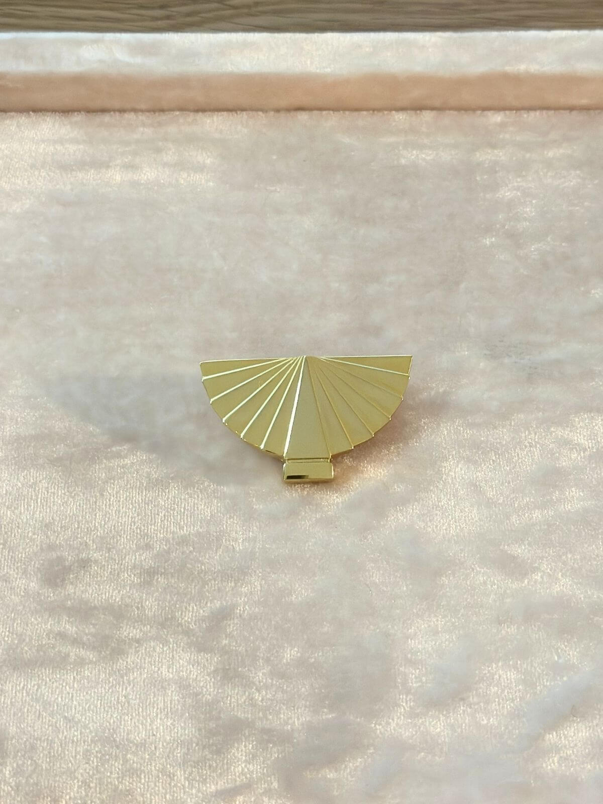 Louise Row Studio vintage Karl Lagerfeld gold fan brooch on pink display pad.