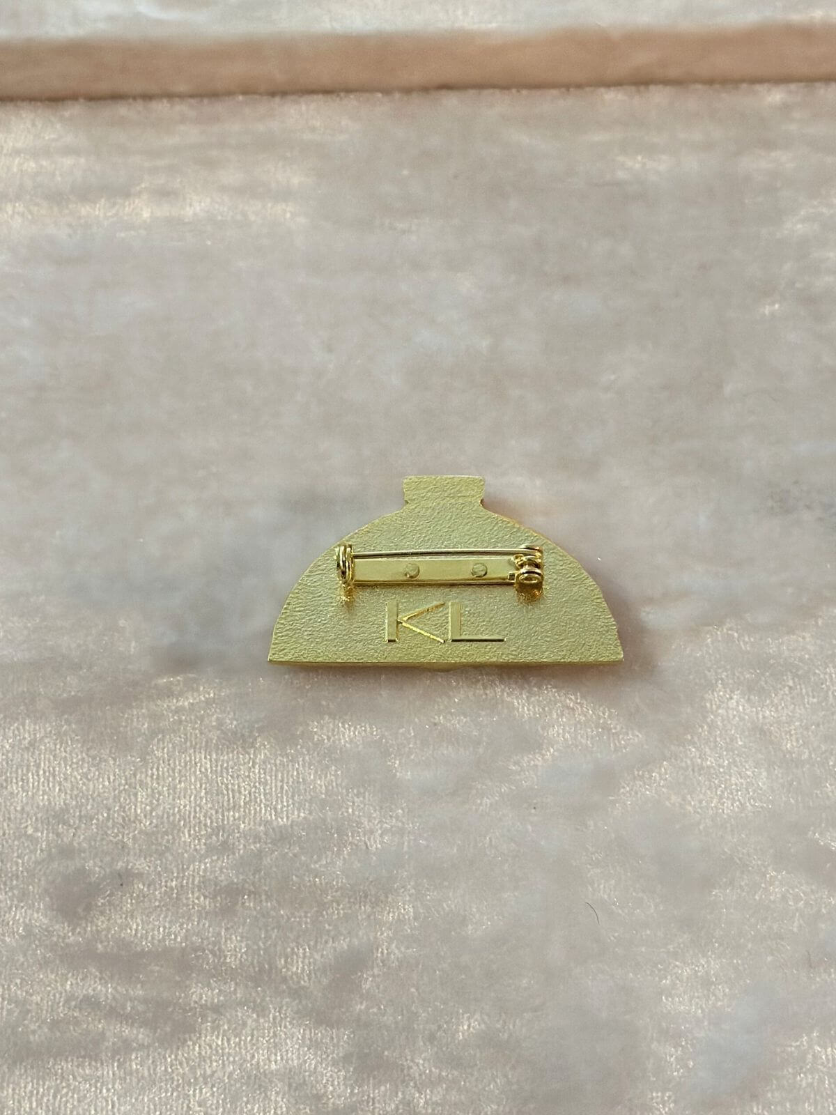 Gold fan sharped brooch back side with KL intial