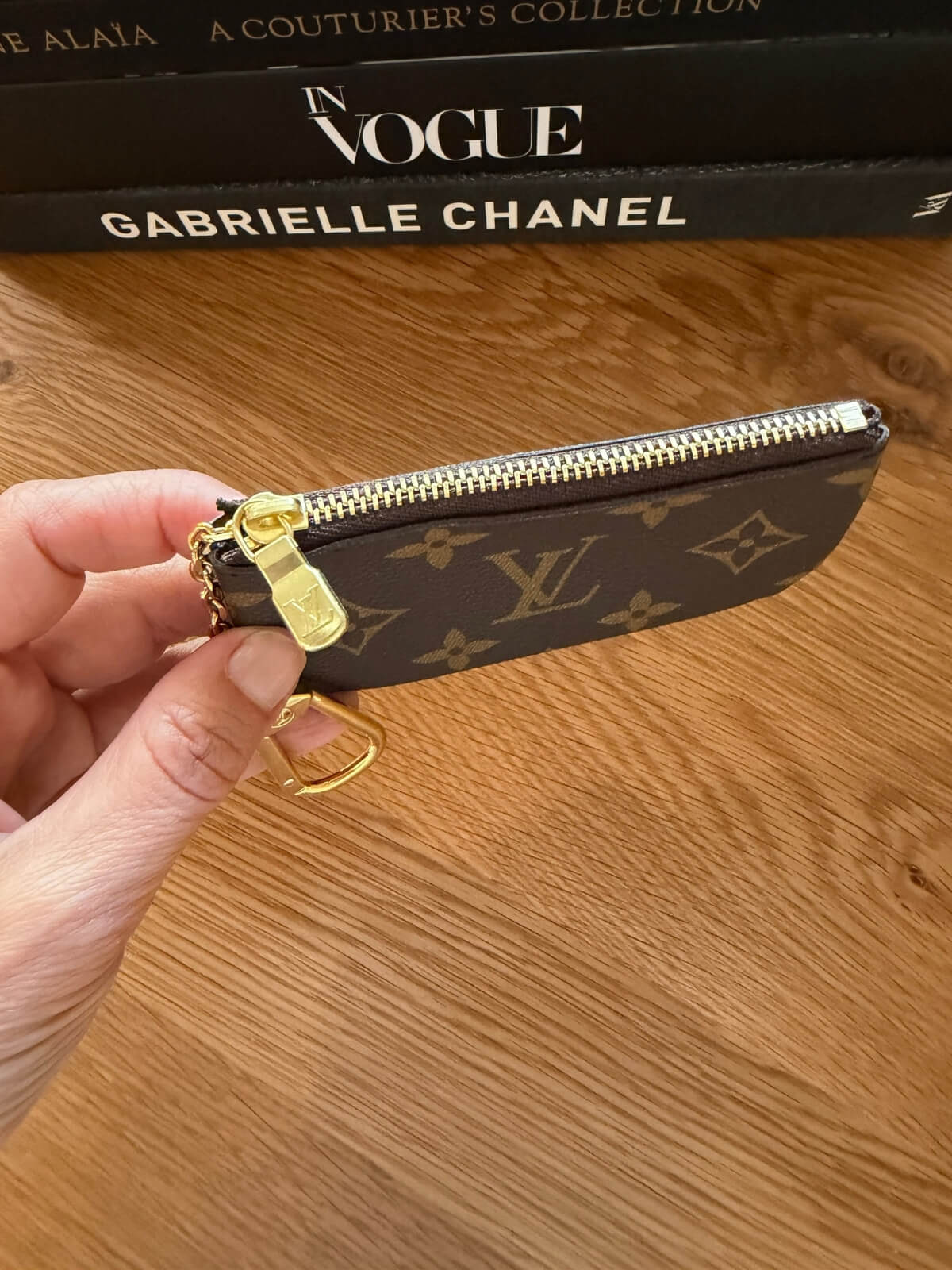 Louise Row featuring LV key pouch on table with books.