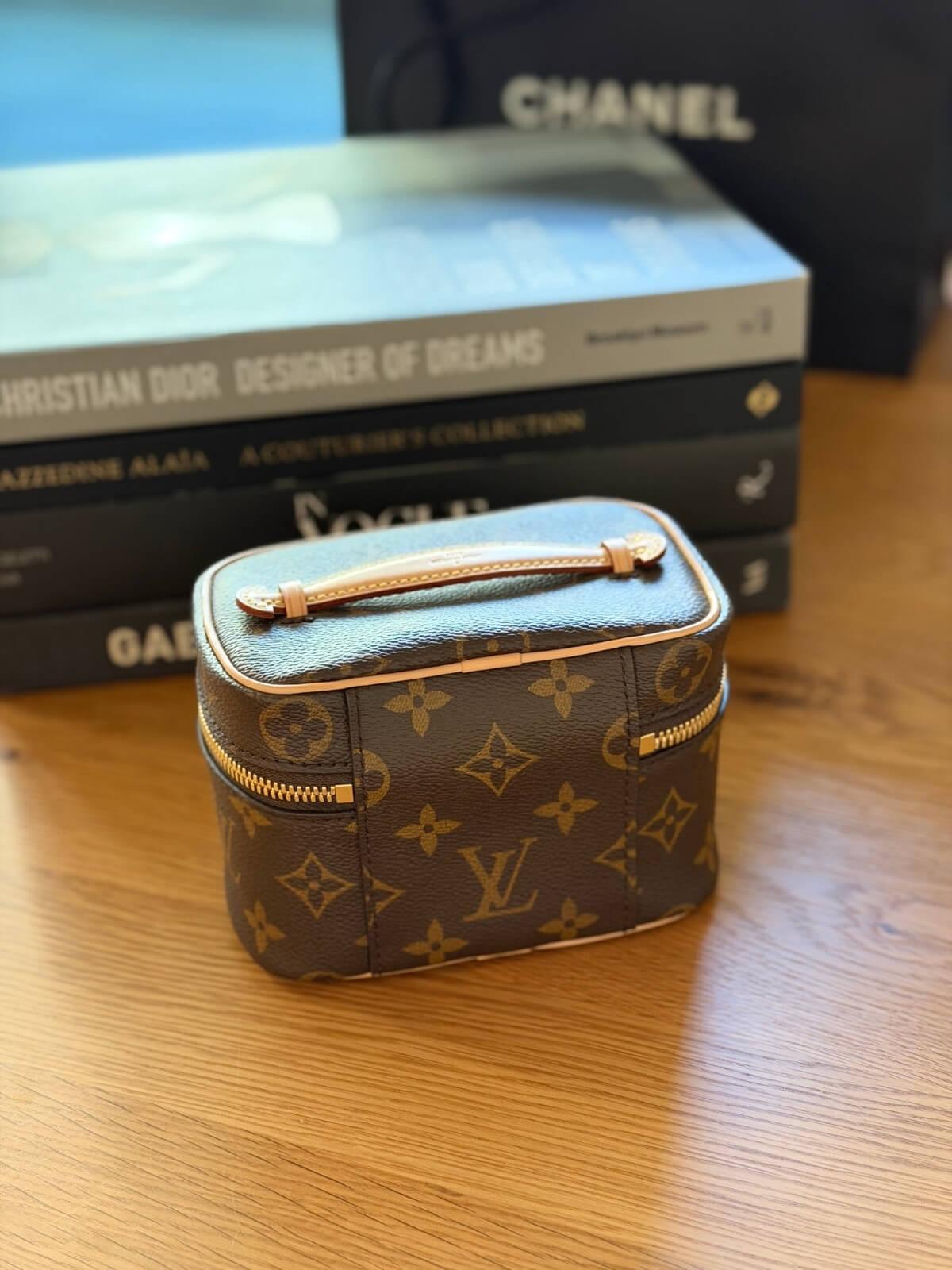 Louise Row featuring Louis Vuitton Nice Nano Vanity case on table with books