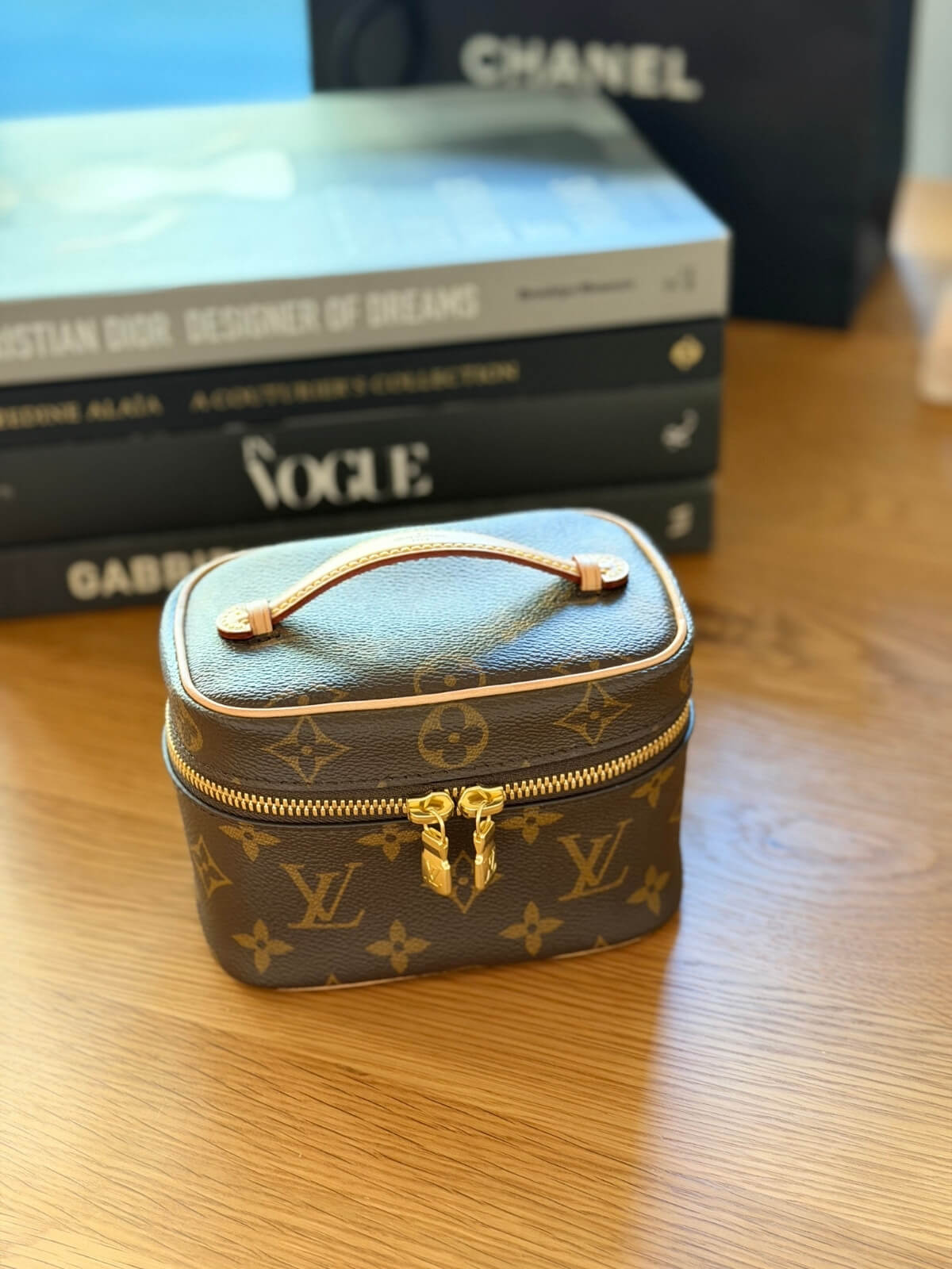 Louise Row featuring Louis Vuitton Nice Nano Vanity case on table with books