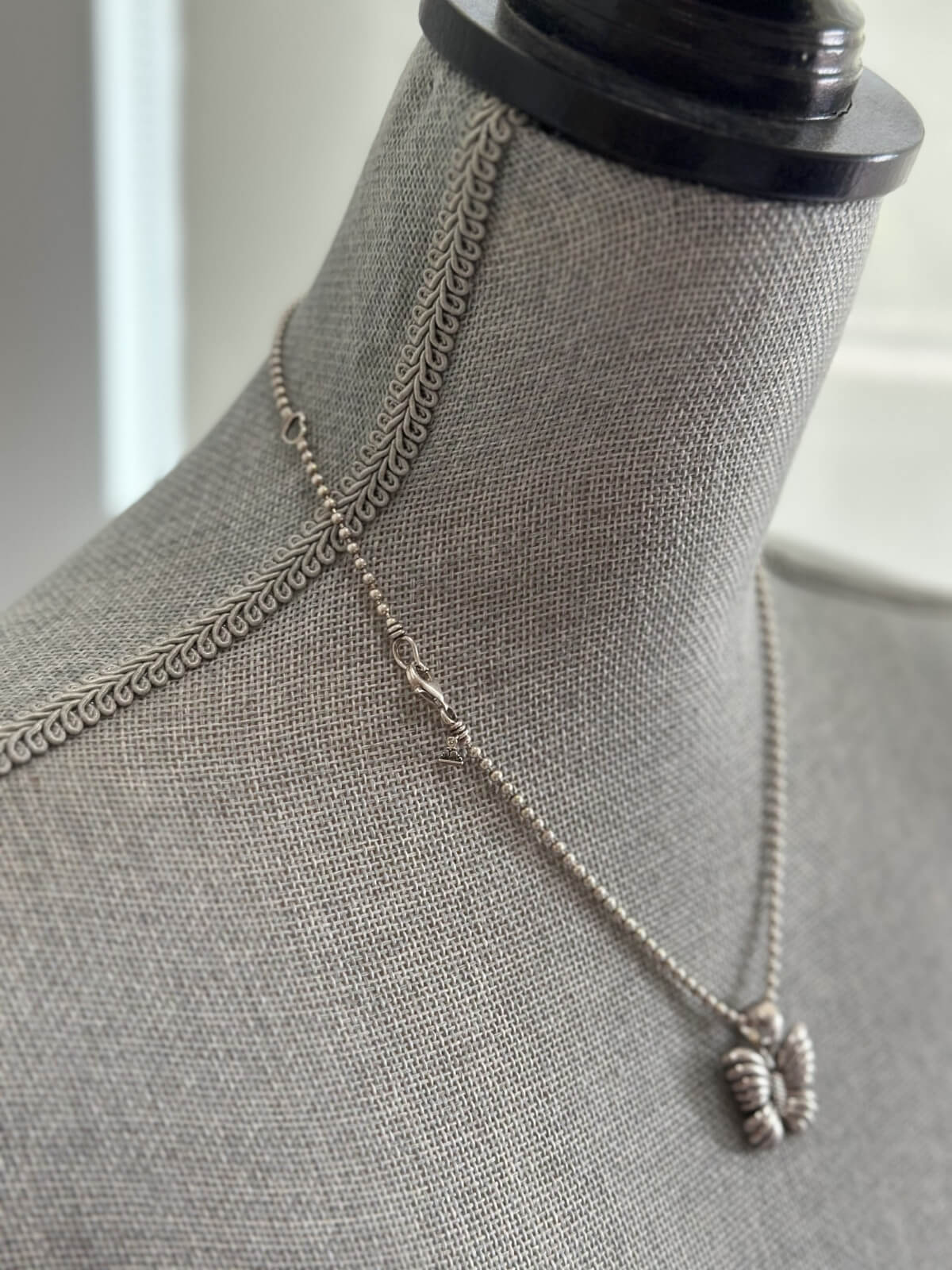 Louise Row featuring Lagos silver butterfly necklace on grey mannequin
