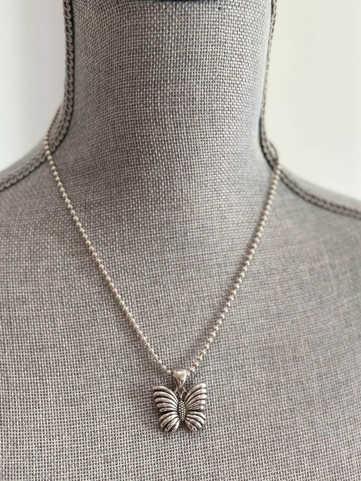 Louise Row featuring Lagos silver butterfly necklace on grey mannequin
