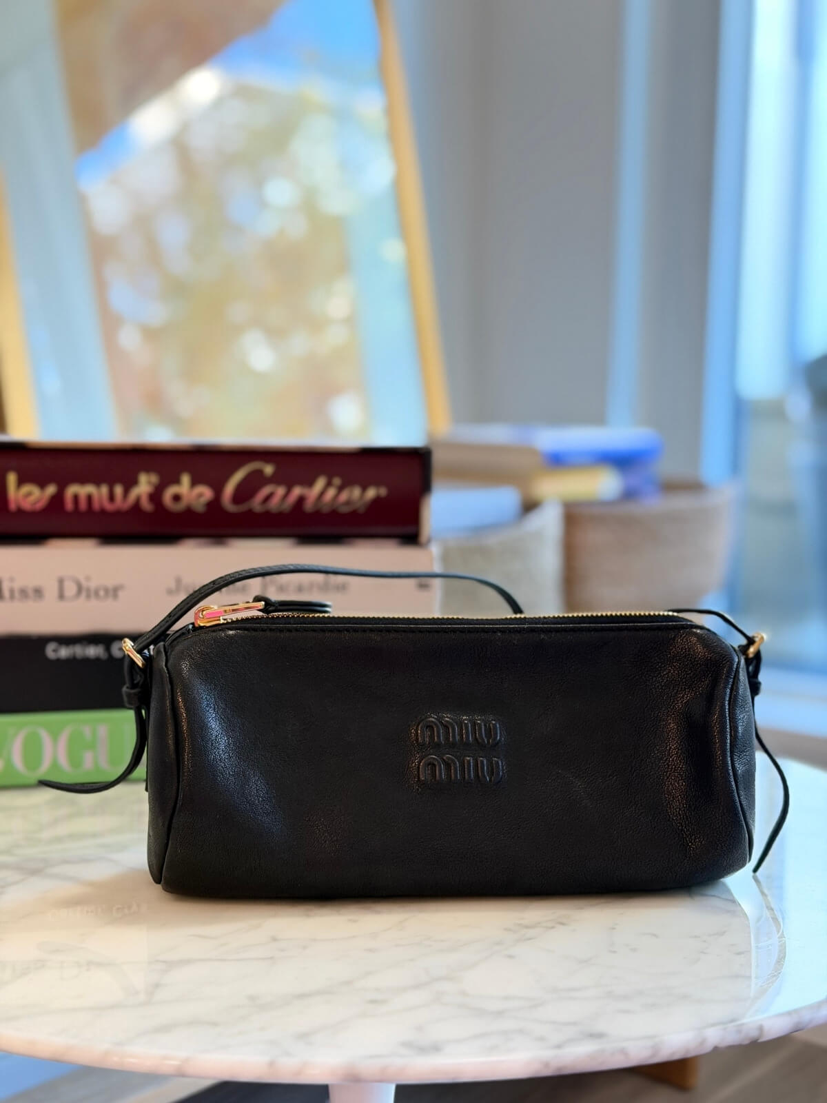 Louise Row featuring Miu Miu Nappa Black shoulder bag on table with books