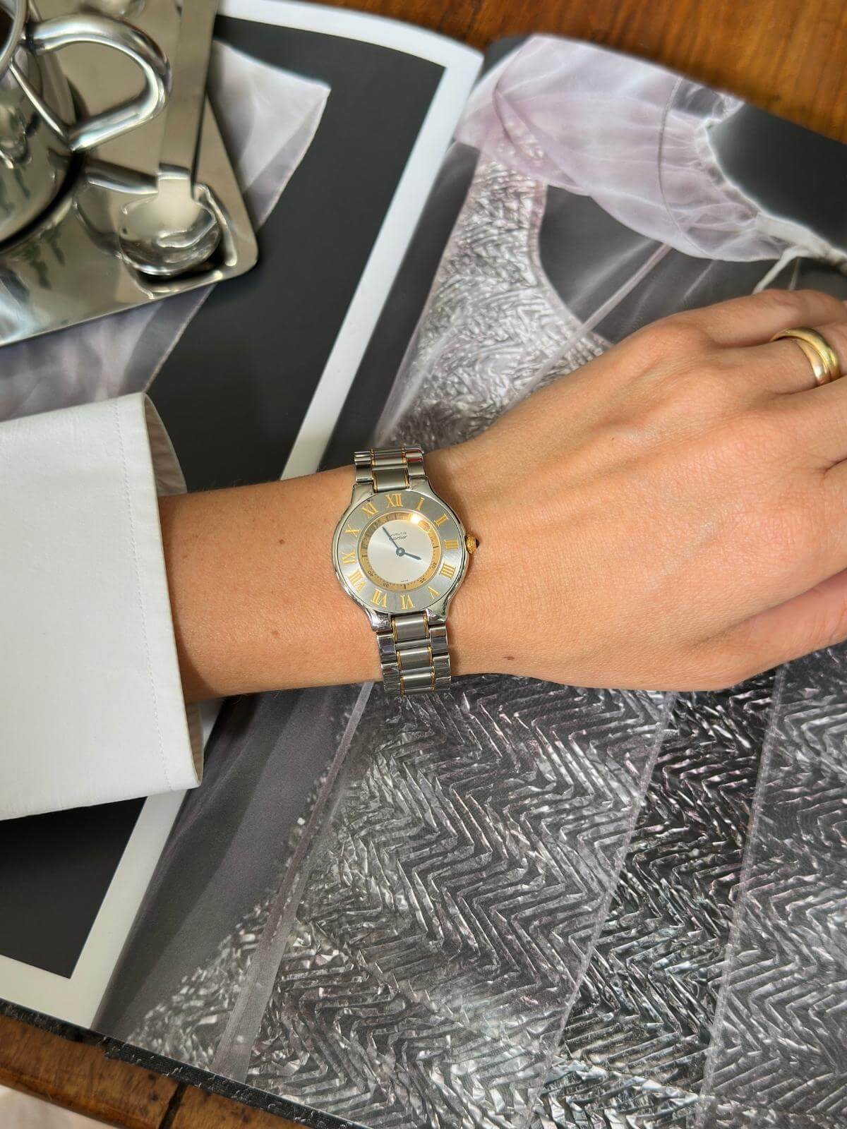 Silver  Cartier watch on a wrist with a patterned surface in the background
