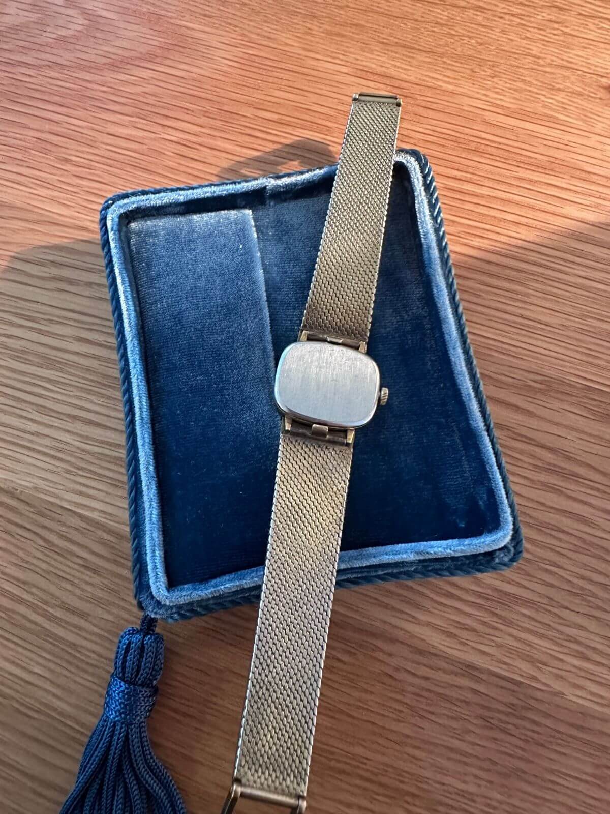 Louise Row Studio featuring Back of Gold Omega De Ville watch on wood table