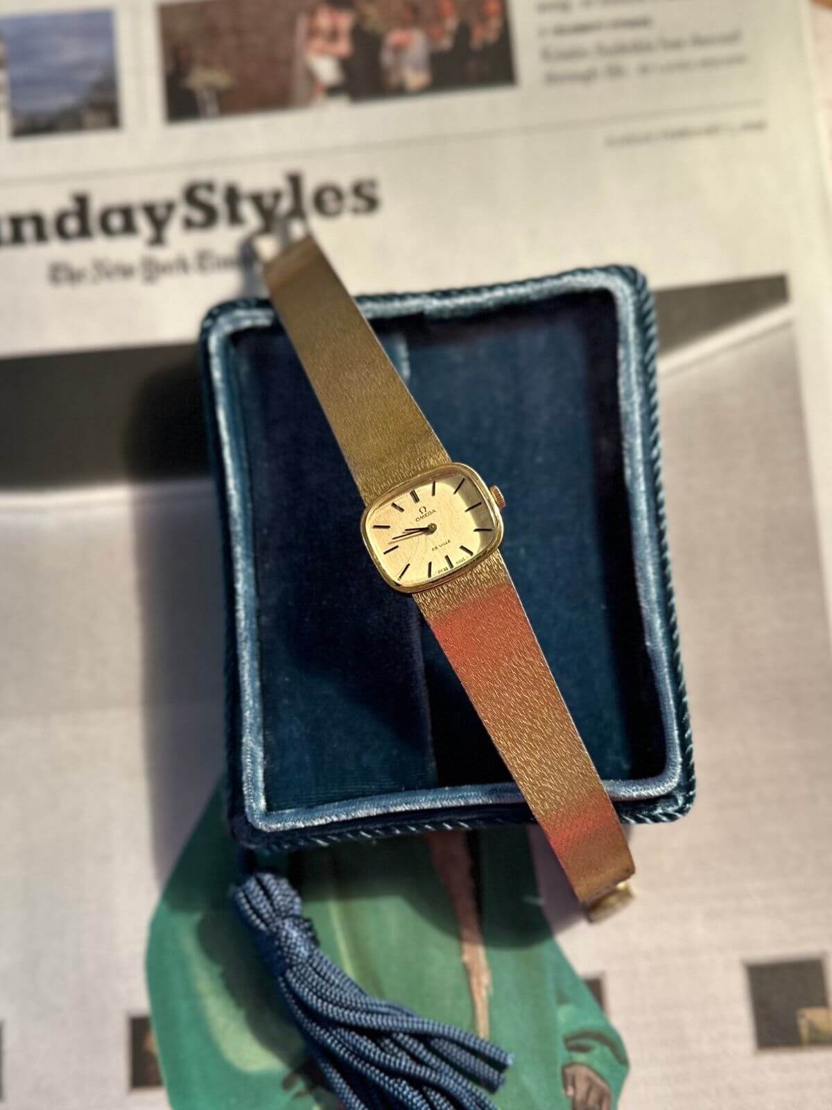 Gold Omega De Ville watch with papers in background
