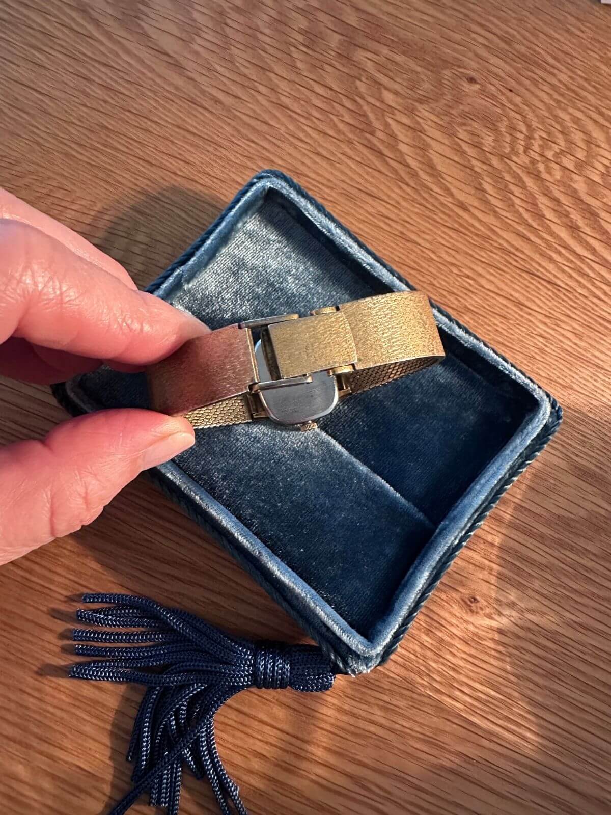 Buckle  of Gold Omega De Ville watch on wood table