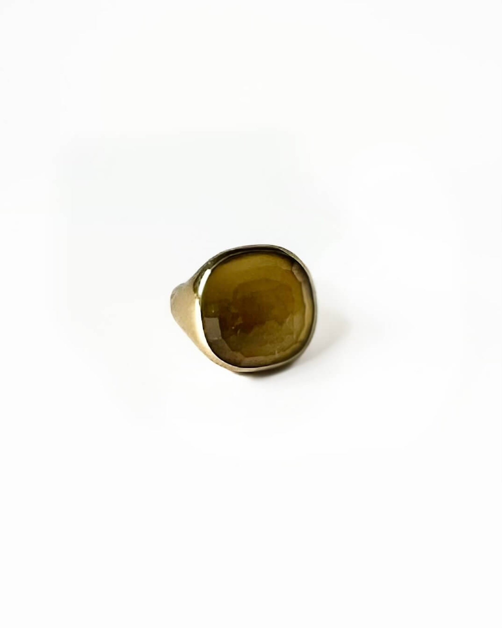 Gold ring with a large green stone on a white background