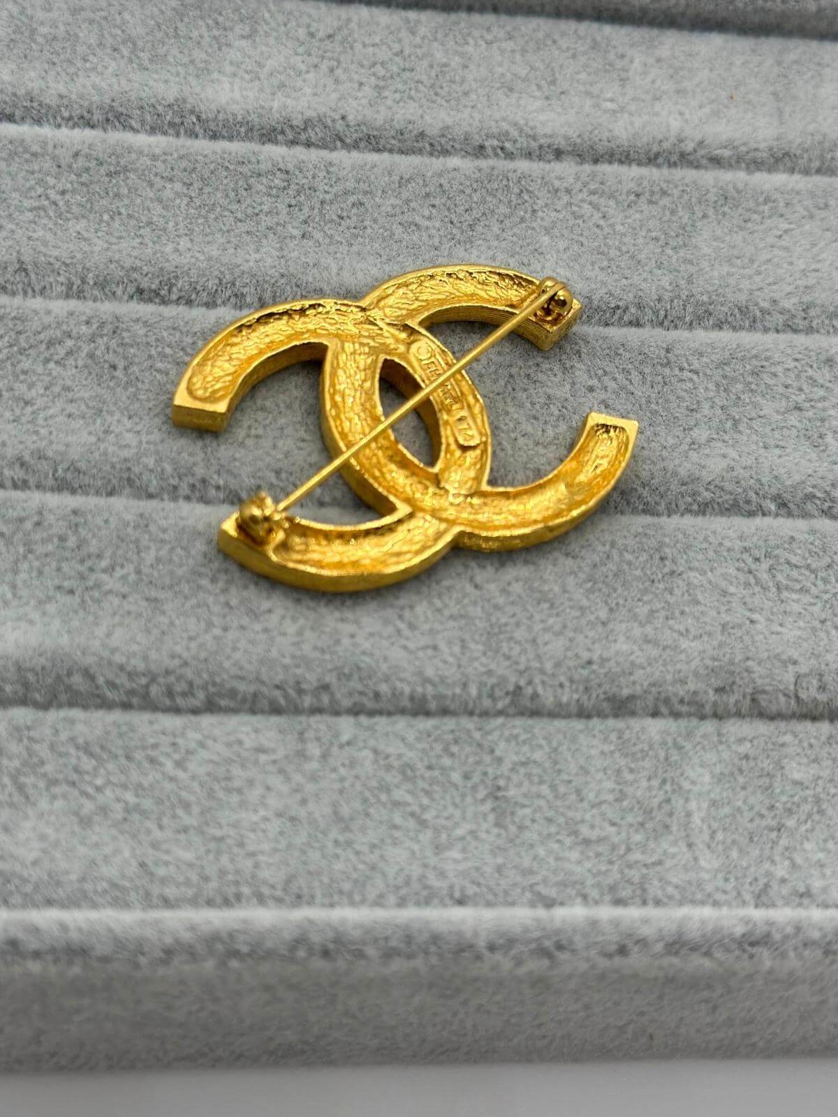 Pre-loved Chanel crystal brooch on grey background showing back side with pin closure