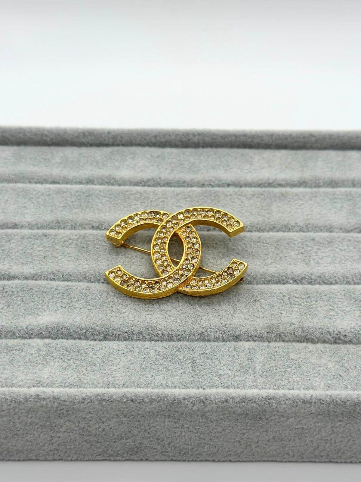 Pre-loved Chanel crystal brooch on grey background