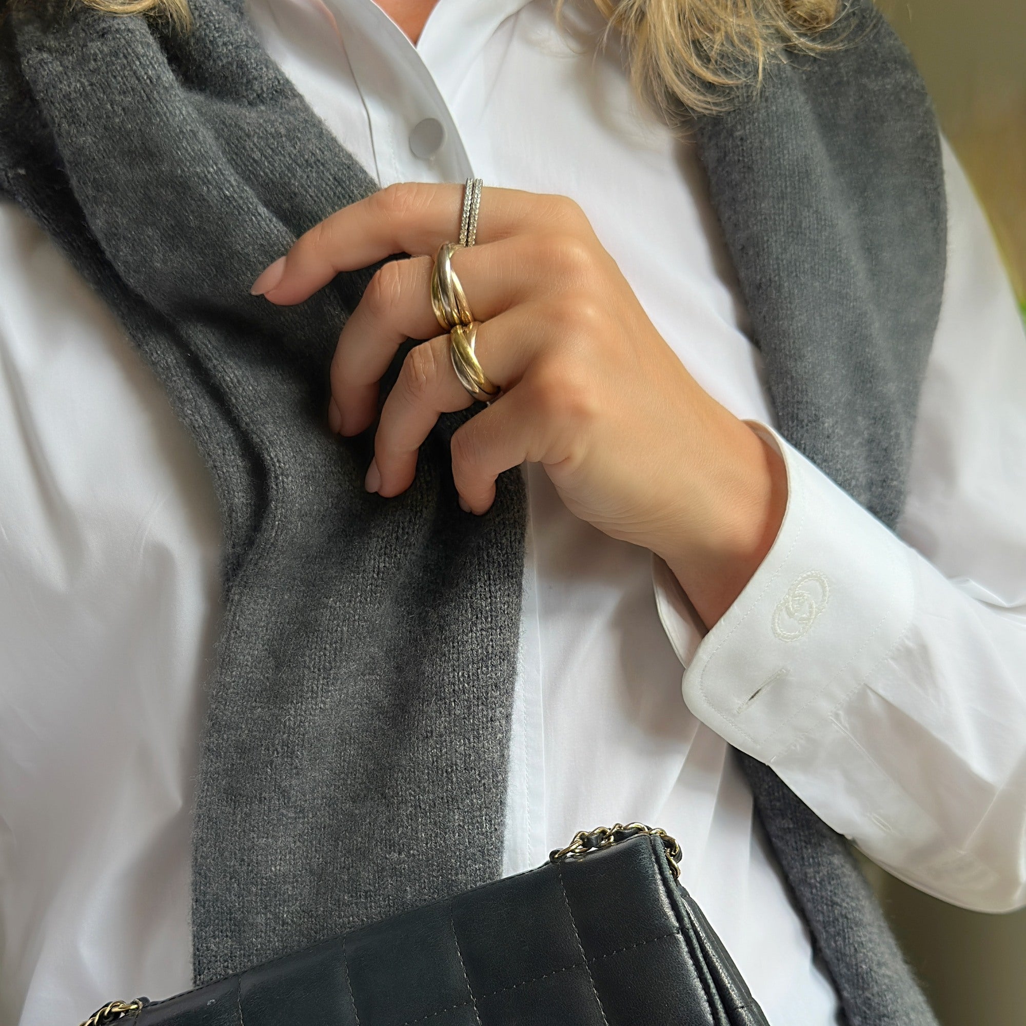 Louise Row featuring model wearing Cartier rings holding sweater and wearing a white shirt. 