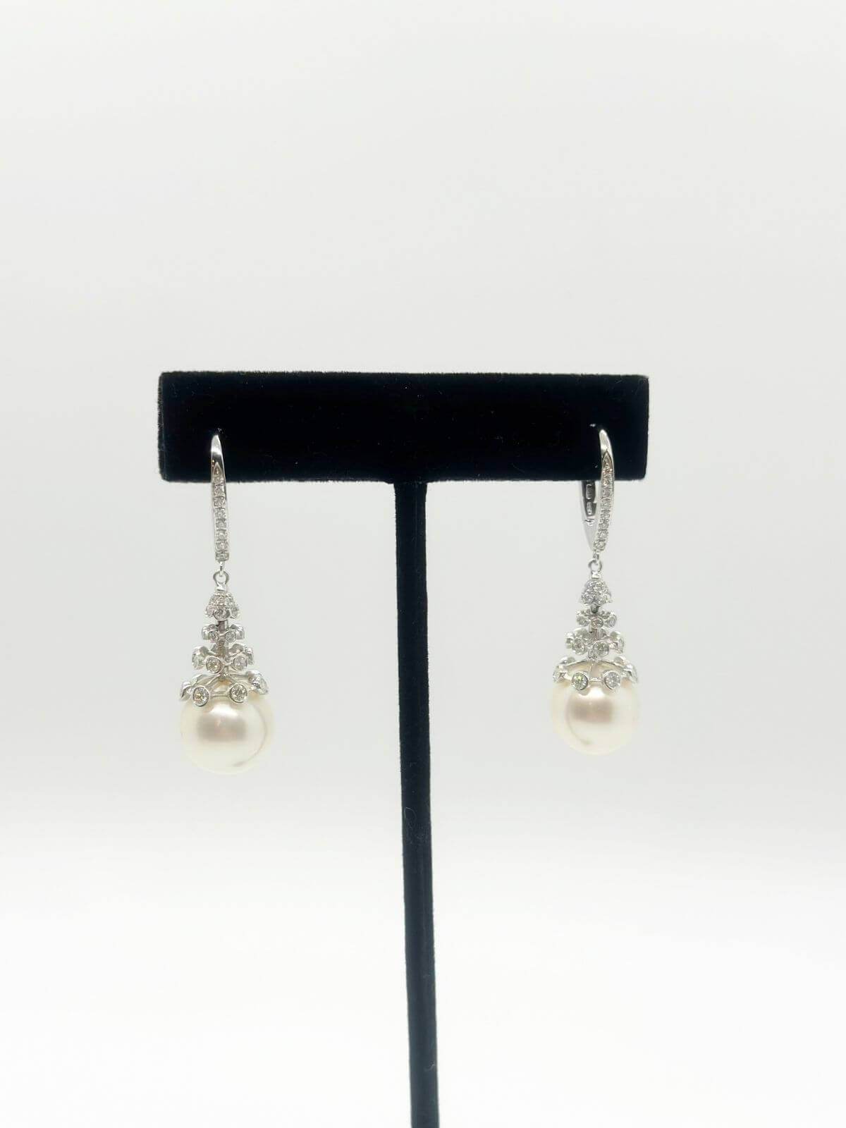 South Sea pearl and diamond drop earring with white background and on black fixture. 