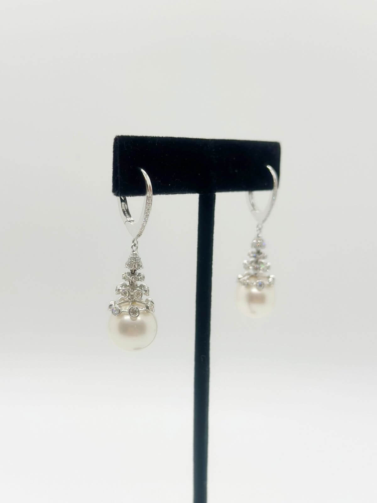 South Sea pearl and diamond drop earring with white background and on black fixture. 