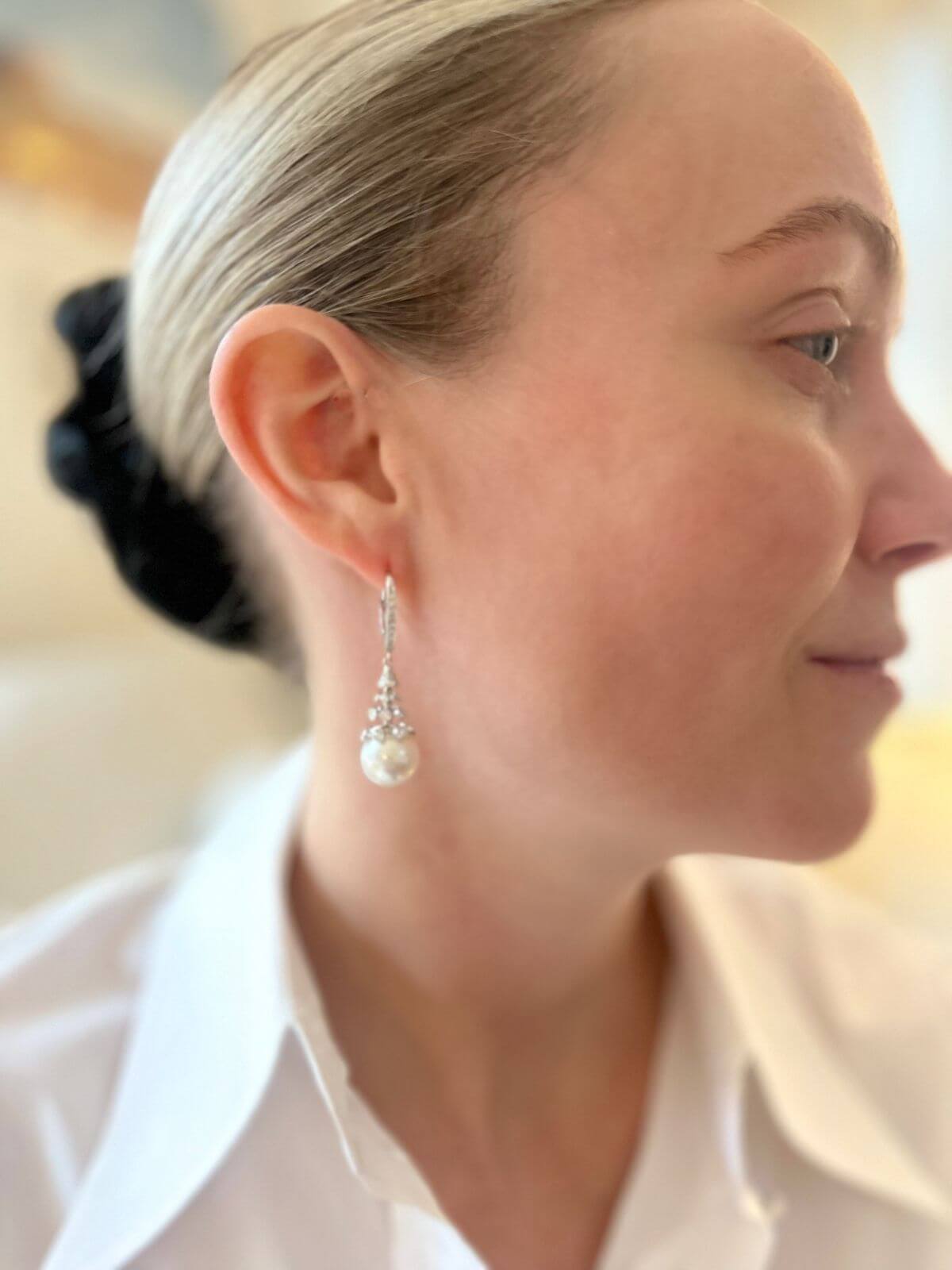 Close-up of a woman wearing pearl earrings with a blurred background