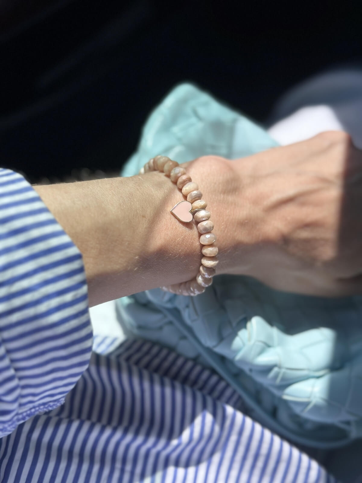 Louise Row Studio featuring Sydney Evan pink bead bracelet on wrist with striped shirt and bag.