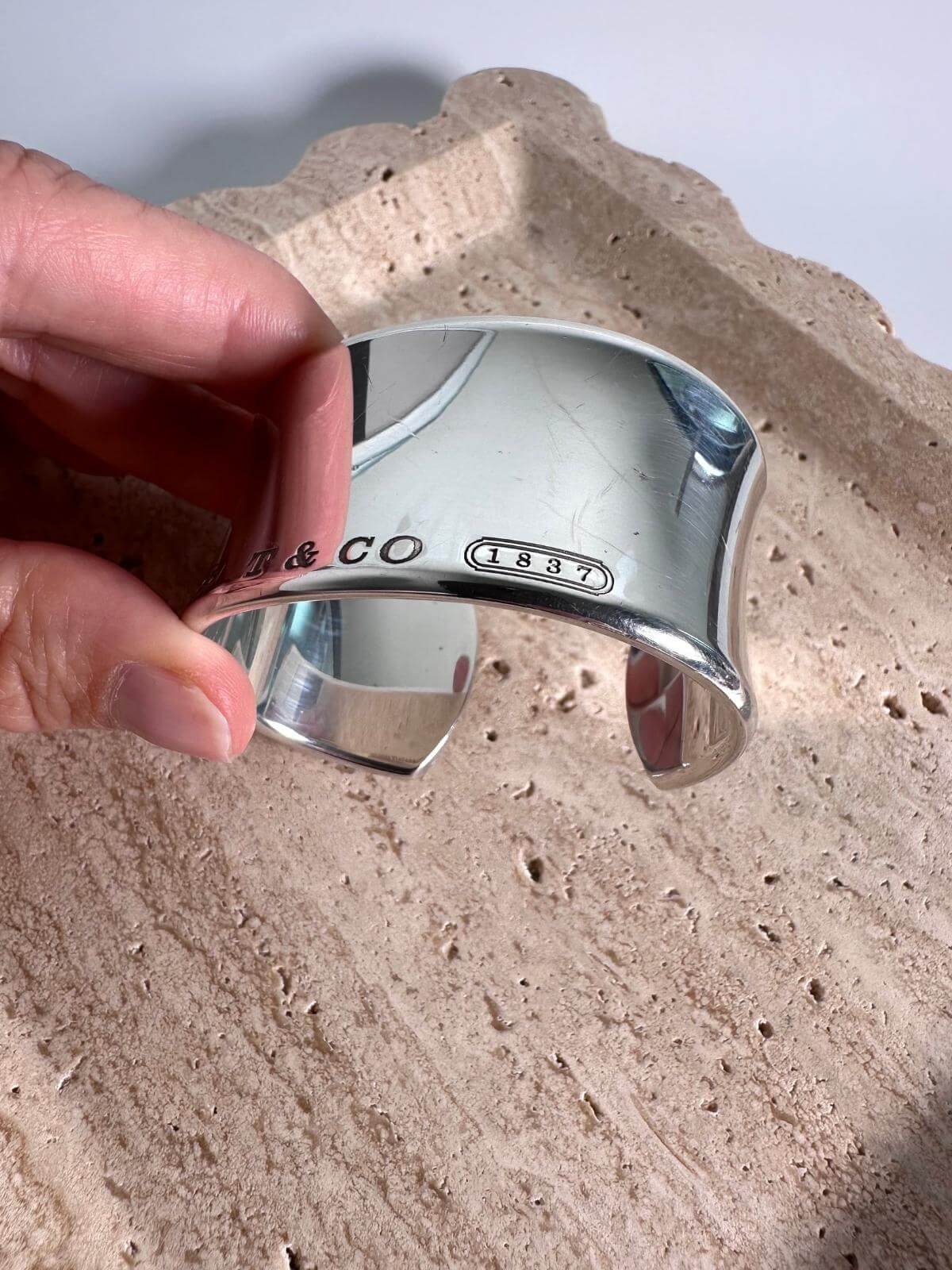 Silver cuff bracelet with 'T & Co' engraving on a marble plate