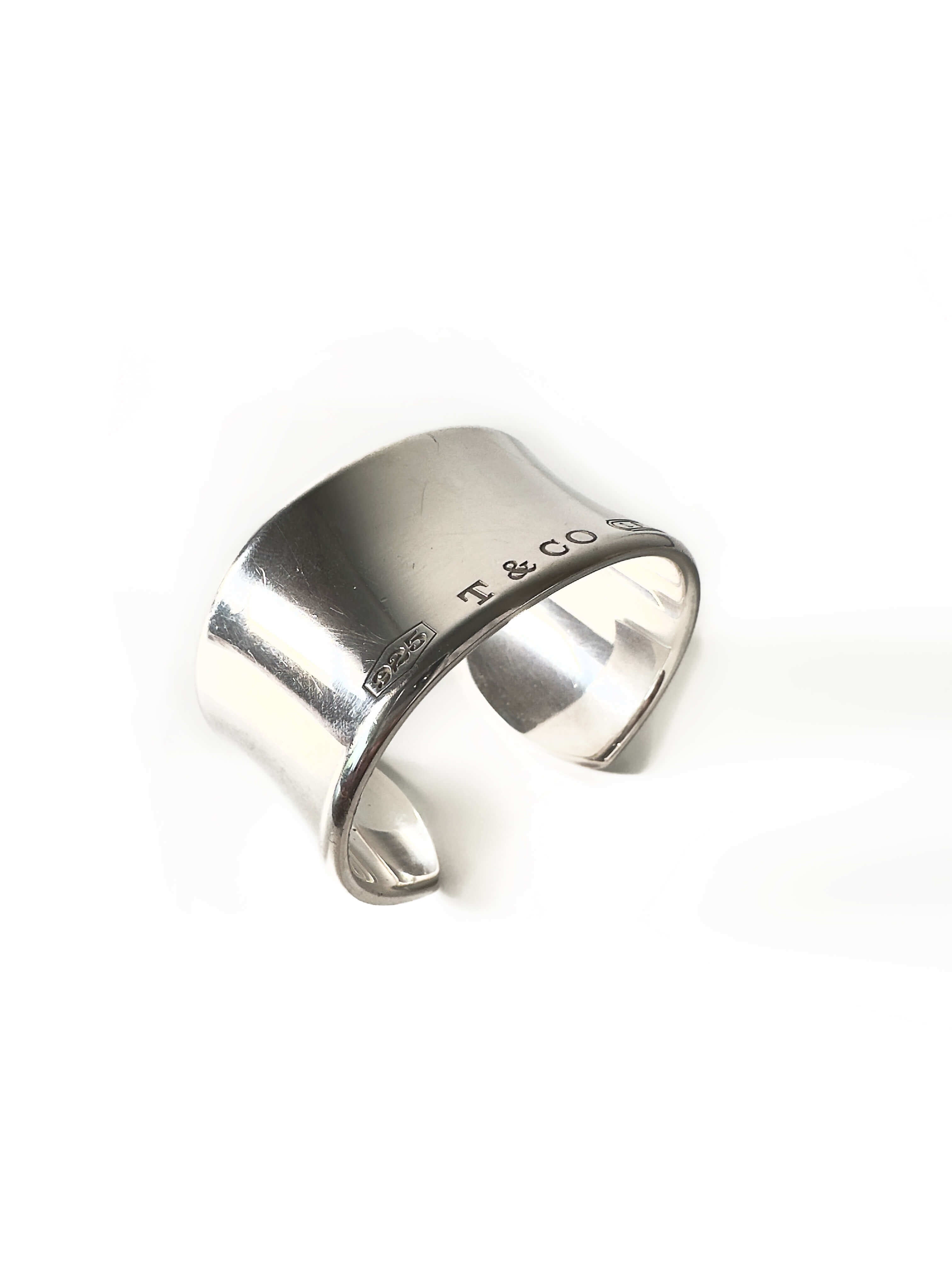 Silver cuff bracelet with 'T & Co' engraving on a white background