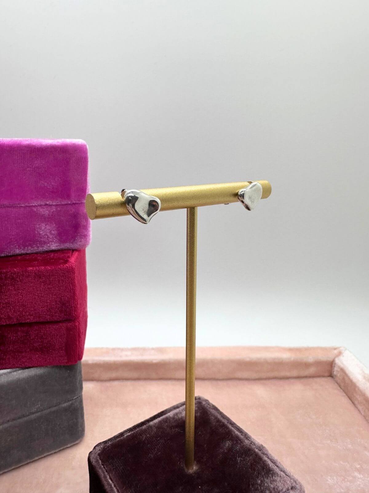 Louise Row Studio featuring Tiffany & Co silver heart stud earrings on fixture with pink boxes in the background. 