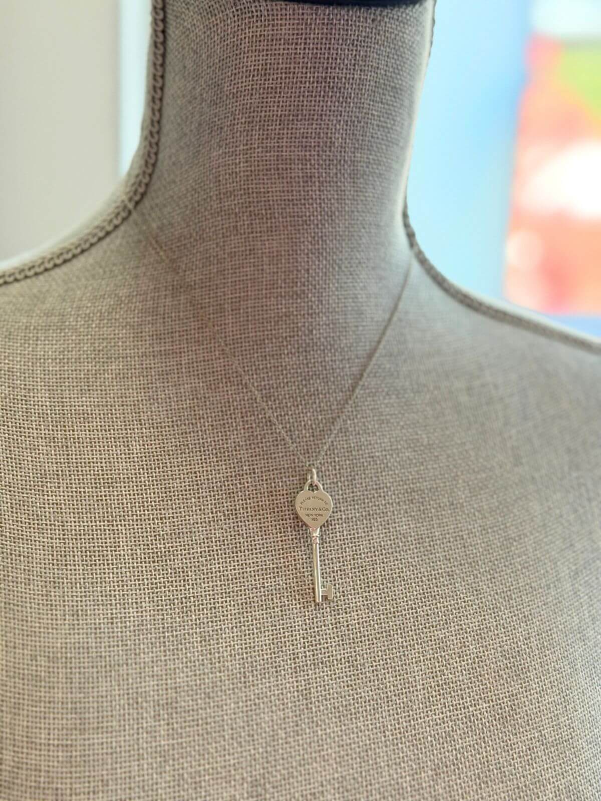Louise Row featuring Tiffany & Co Heart Key Pendant in silver on grey mannequin