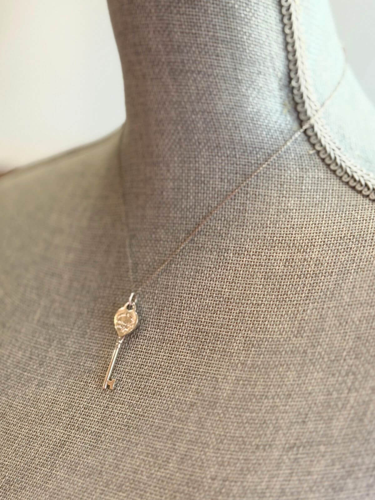 Louise Row featuring Tiffany & Co Heart Key Pendant in silver on grey mannequin