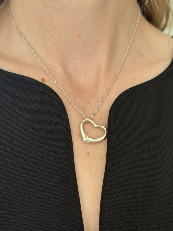 Louise Row Studio featuring model wearing Tiffany and Co silver Open heart necklace on black top.  Showing back of necklace. 