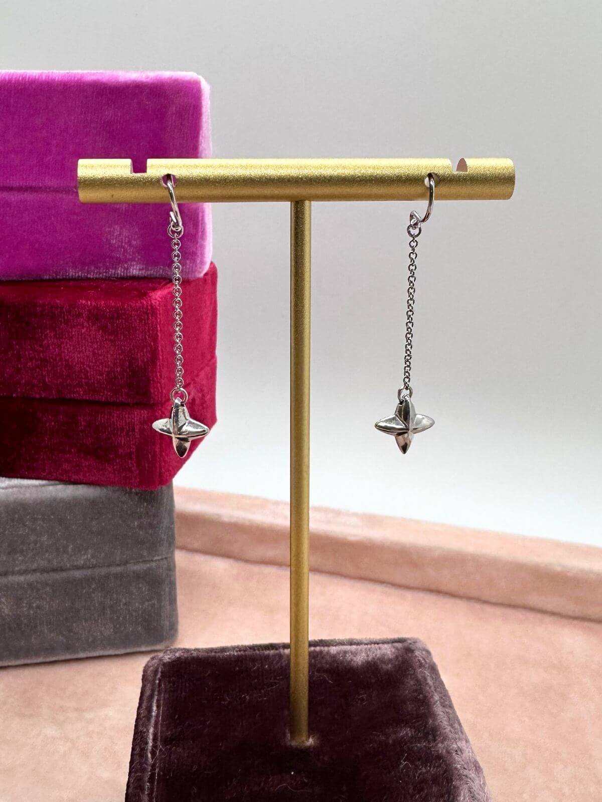 Tiffany Silver star earrings on stand on a gray surface