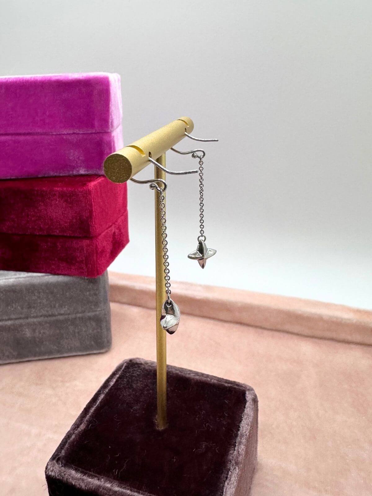 Tiffany Silver star earrings on stand on a gray surface