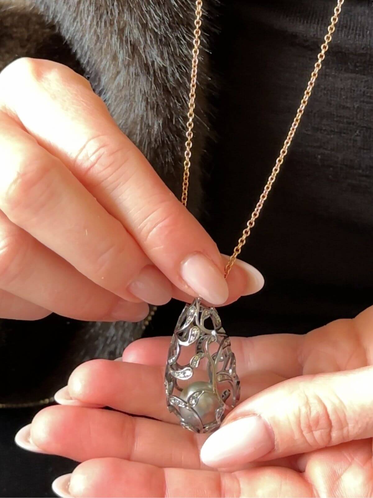 Louise Row Studio featuring Utopia Bolero pearl and diamond necklace on model's Hand holding a silver pendant with a gold chain