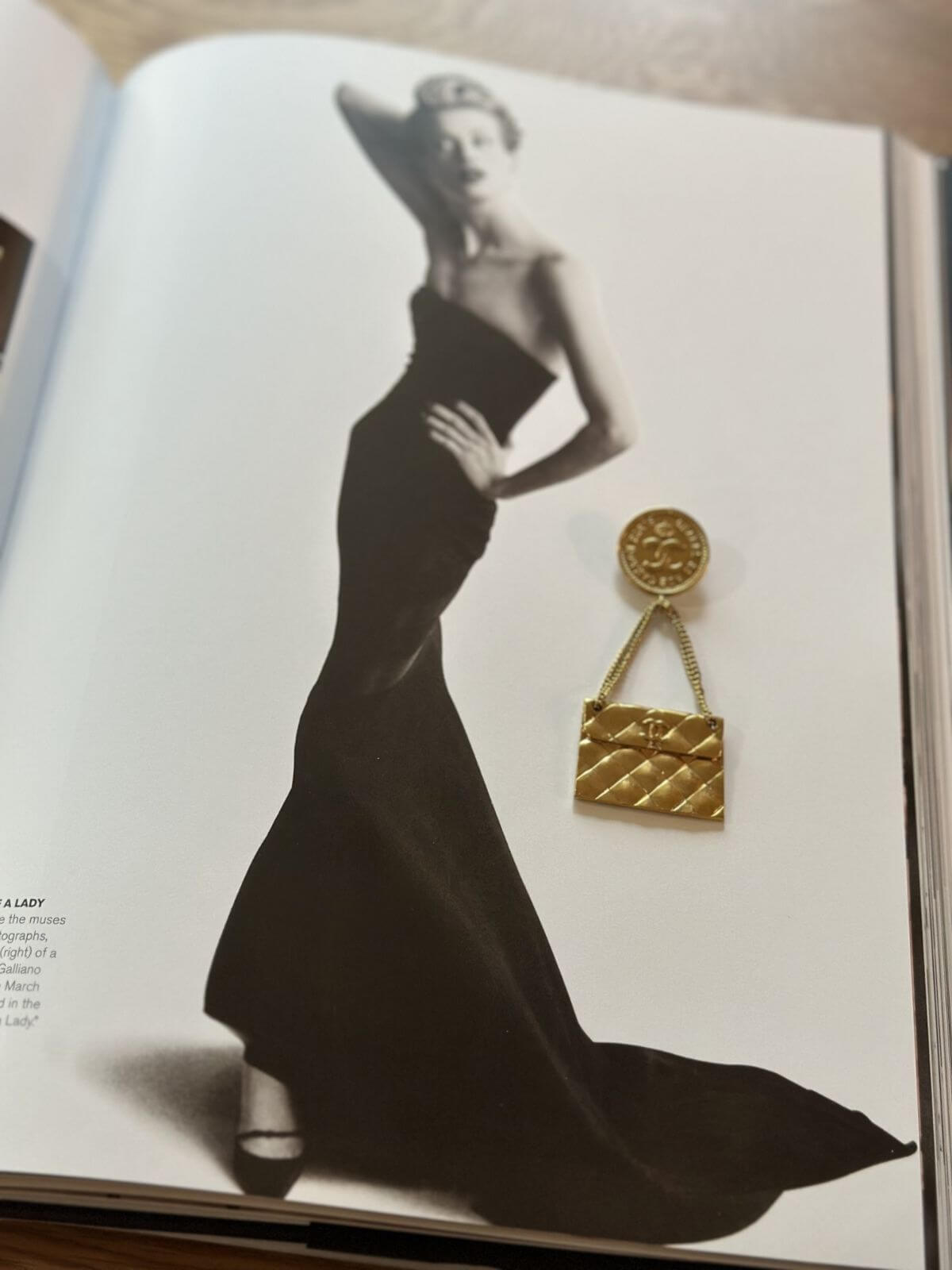 Gold quilted handbag with a prominent clasp on a magazine page featuring a woman in a black gown.
