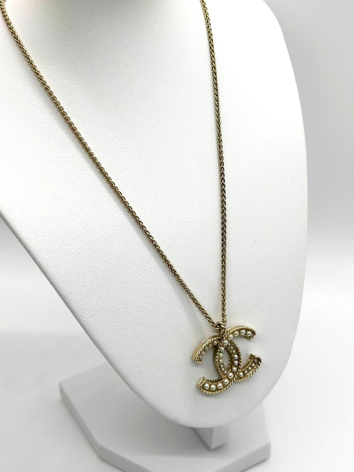 Chanel gold and pearl necklace on white bust form.