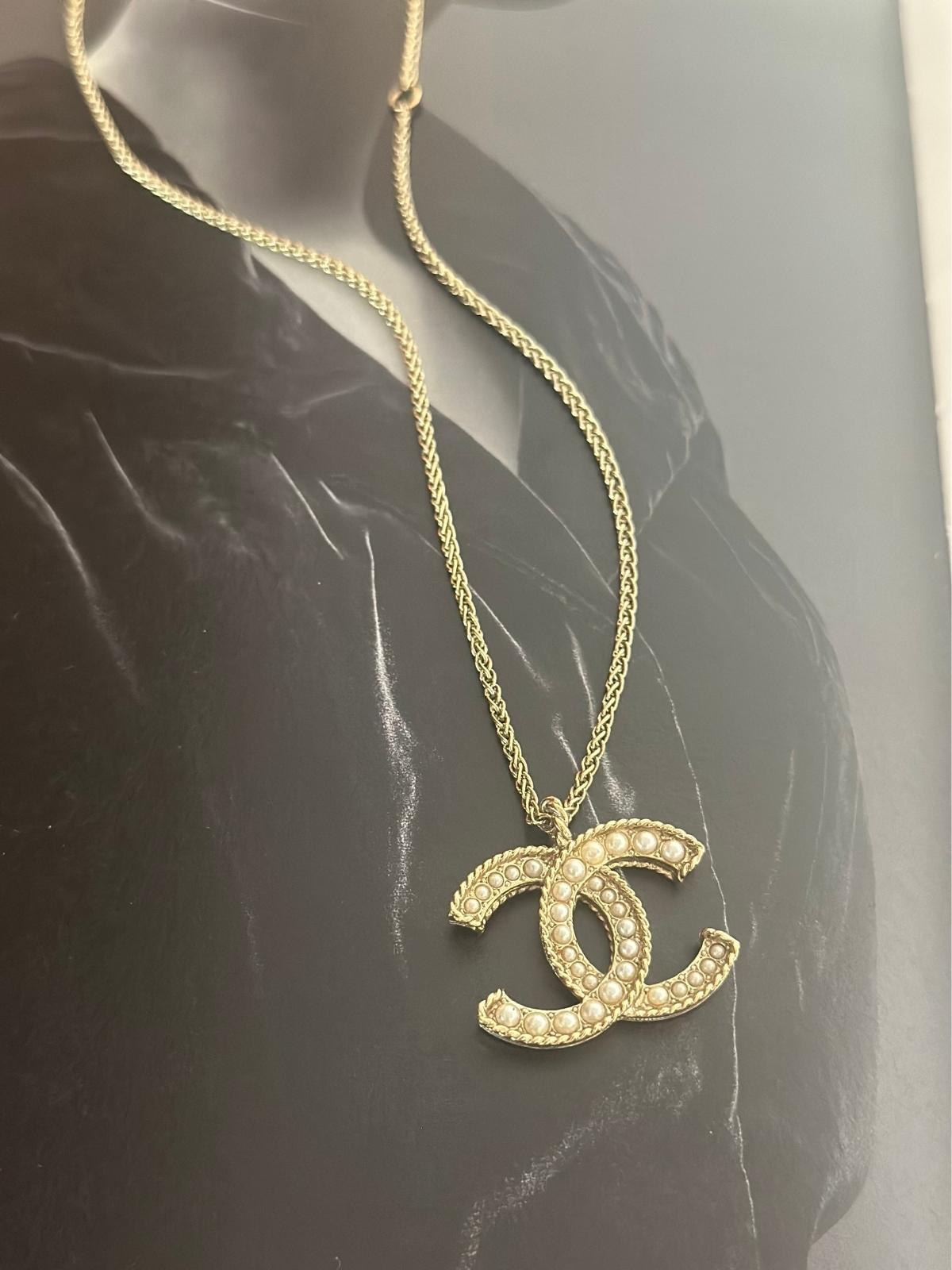 Chanel gold and pearl necklace on black background.