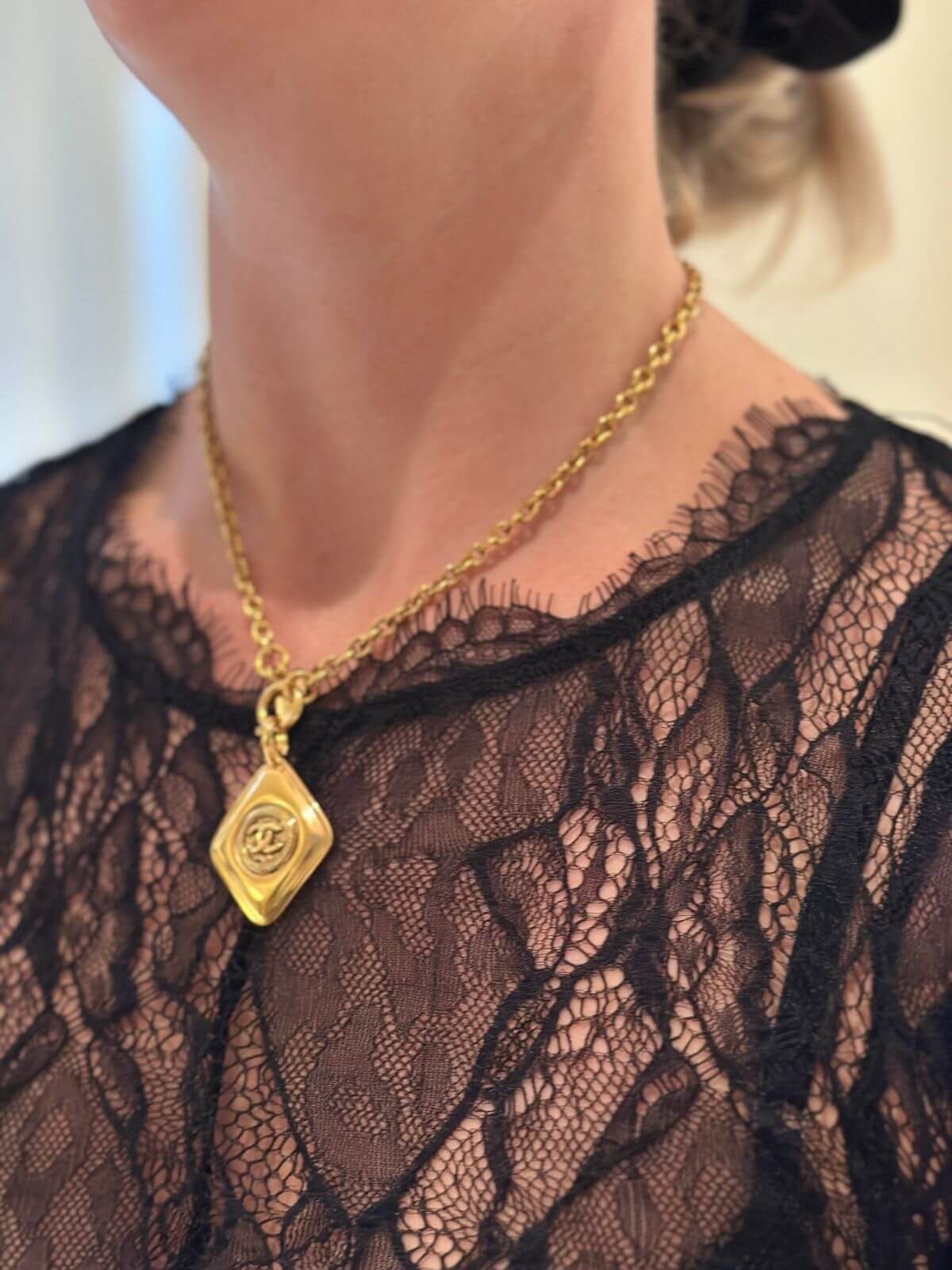Chanel gold diamonds shaped necklace on model with lace top.